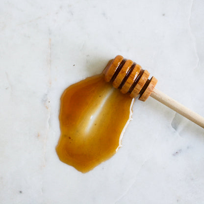 Raw 350+ honey on a wooden dipper — texture proof